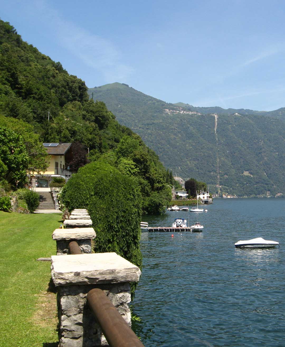 Vista sul pontile privato Telos Boats dal giardino sul lago riservato ai clienti del noleggio barche